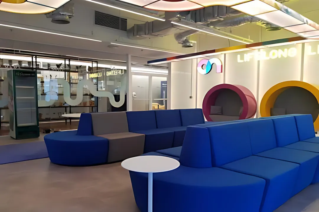 Espaço corporativo da Ambev com sofás azuis e faixas de luz coloridas
