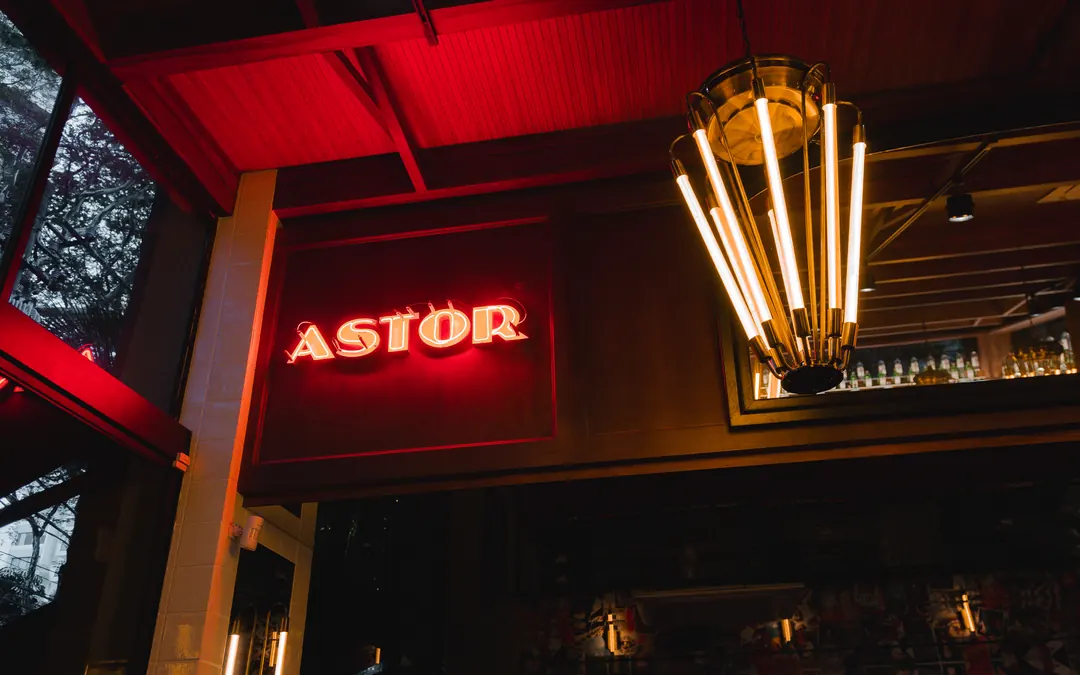 Letreiro Astor em neon e luminária pendente dourada
