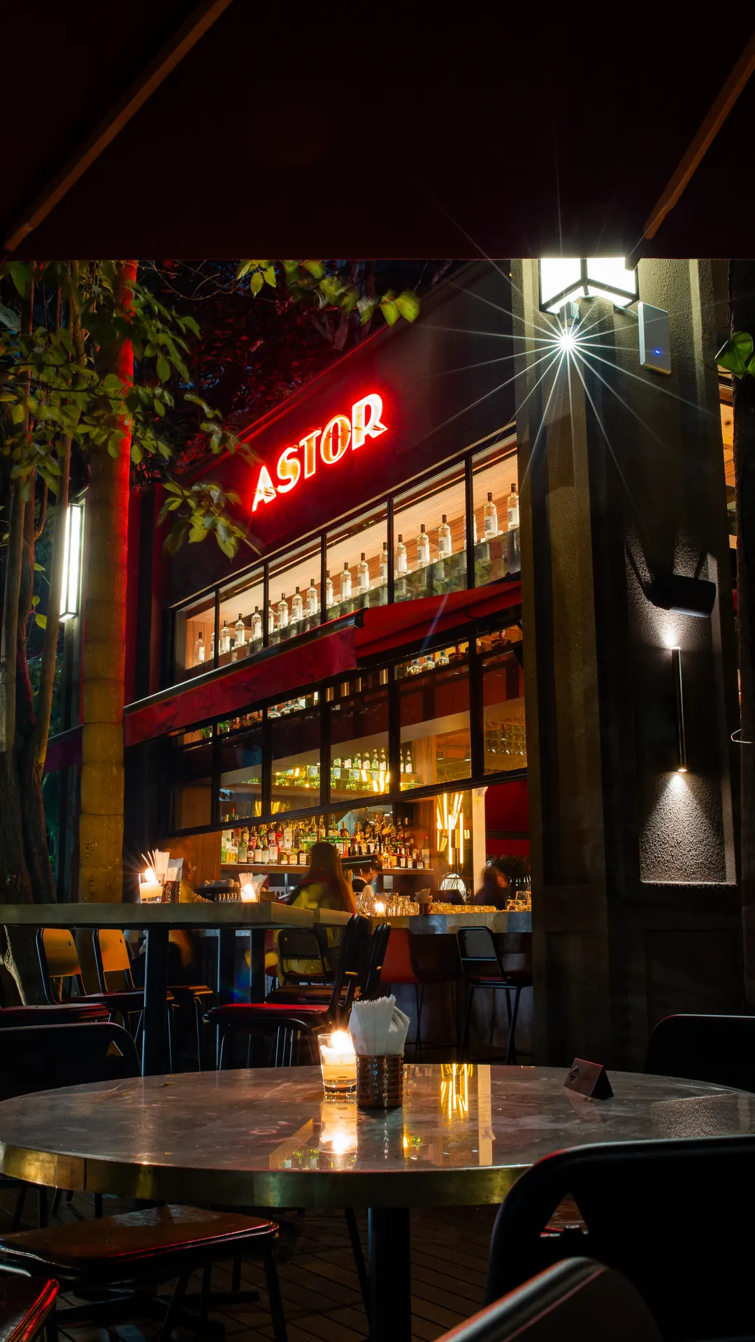 Varanda do Astor à noite, com letreiro e mesas