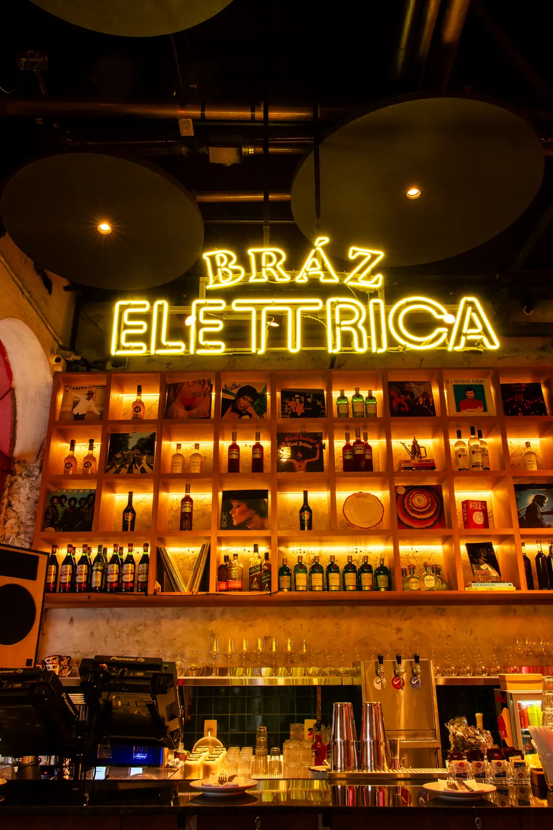 Bar com letreiro em neon e estante de garrafas