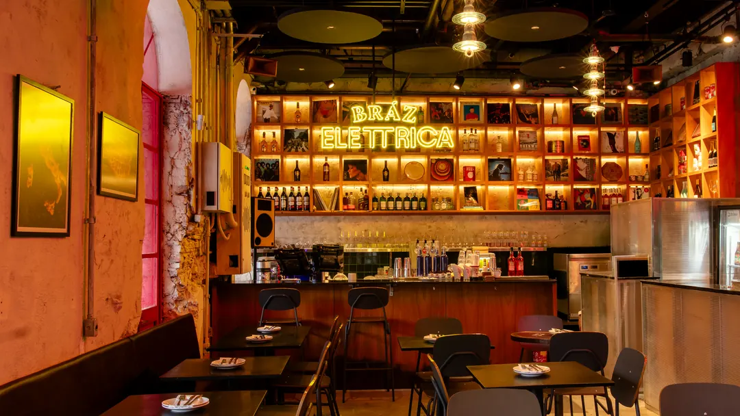Salão com paredes texturizadas, janelas em arco e bar ao fundo
