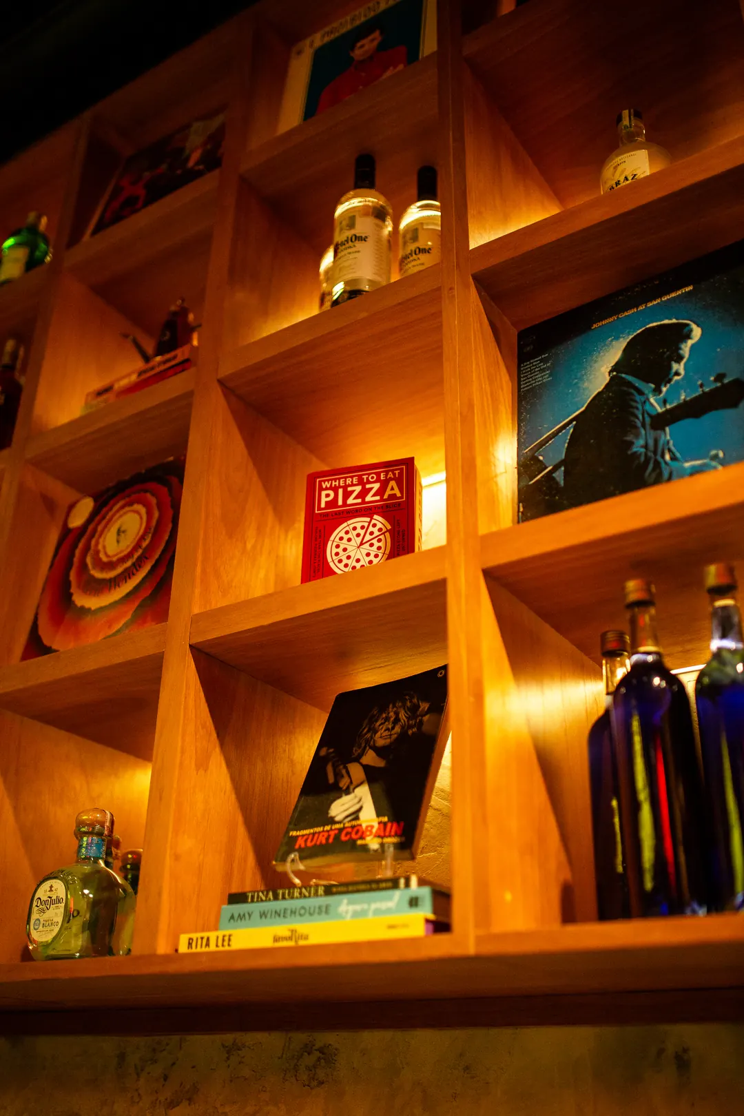 Nichos de madeira com discos, garrafas e objetos