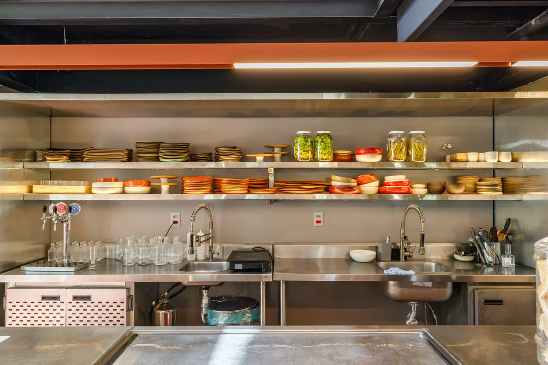 Cozinha aberta em inox com prateleiras de insumos