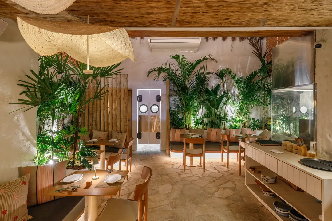 Salão com vegetação, banco em alvenaria e porta de acesso