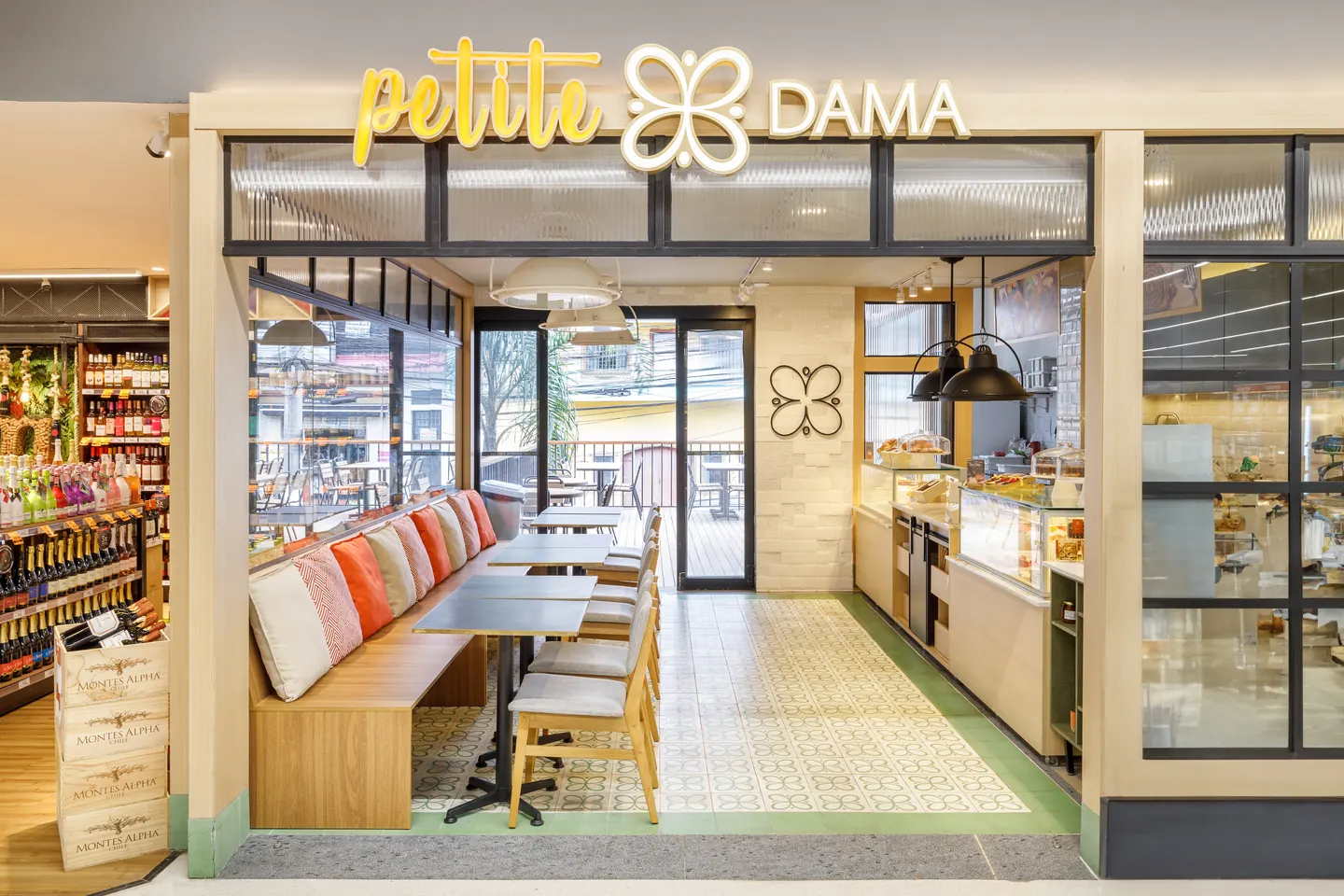 Fachada da Petite Dama com letreiro amarelo e salão com banco estofado