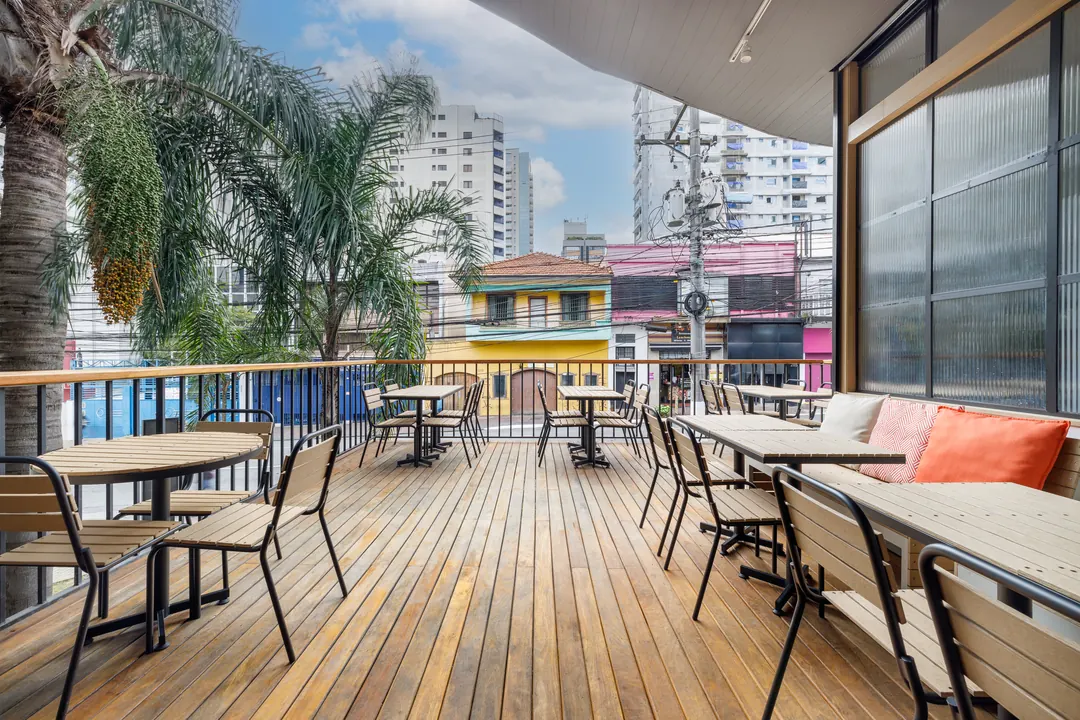 Varanda com deck de madeira, mesas e vista para a rua