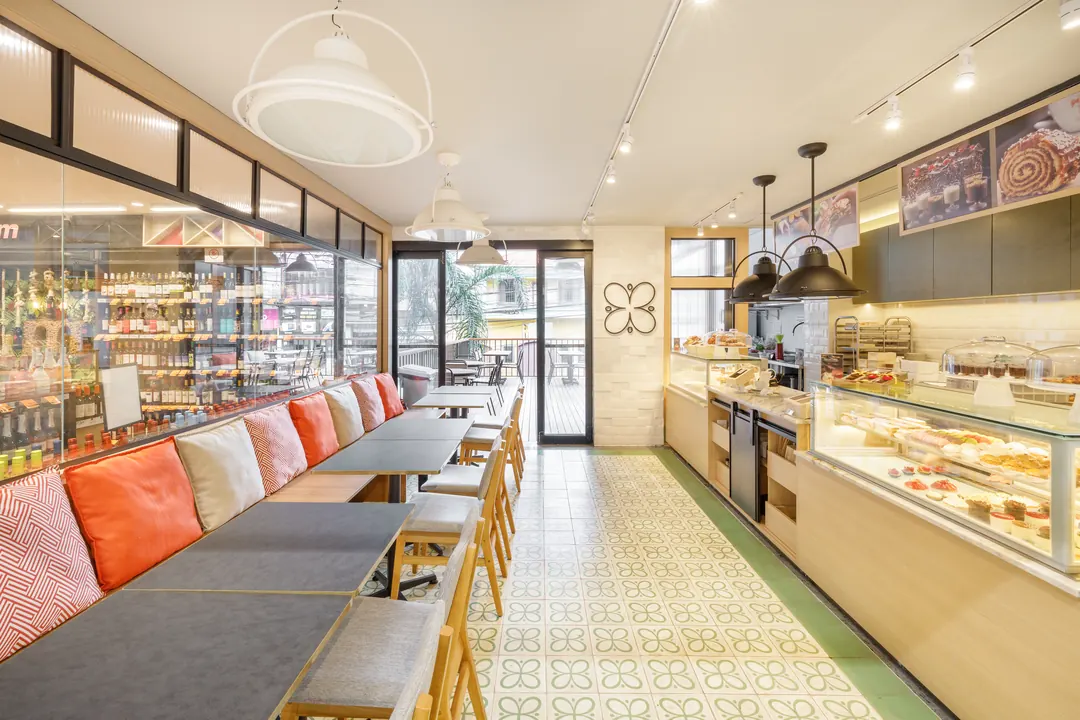 Salão com banco corrido, luminárias pendentes e vitrine de doces